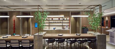 A modern conference room with a long table, multiple chairs, and a central plant.