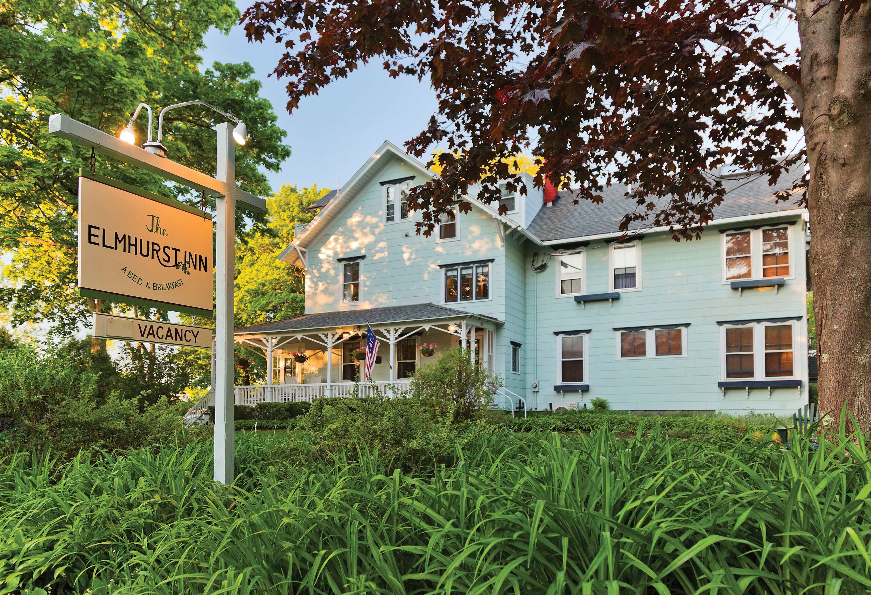 A light blue house with a porch and a sign indicating a vacancy.