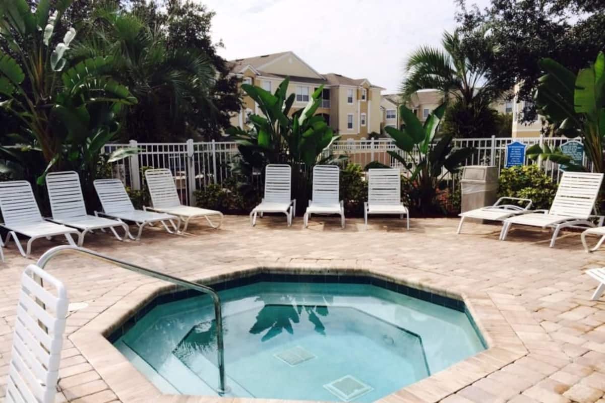 Une piscine entourée de chaises longues blanches et d’une terrasse en briques.