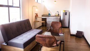 A modern living space with a sofa, chairs, a dining table, and a kitchen area.