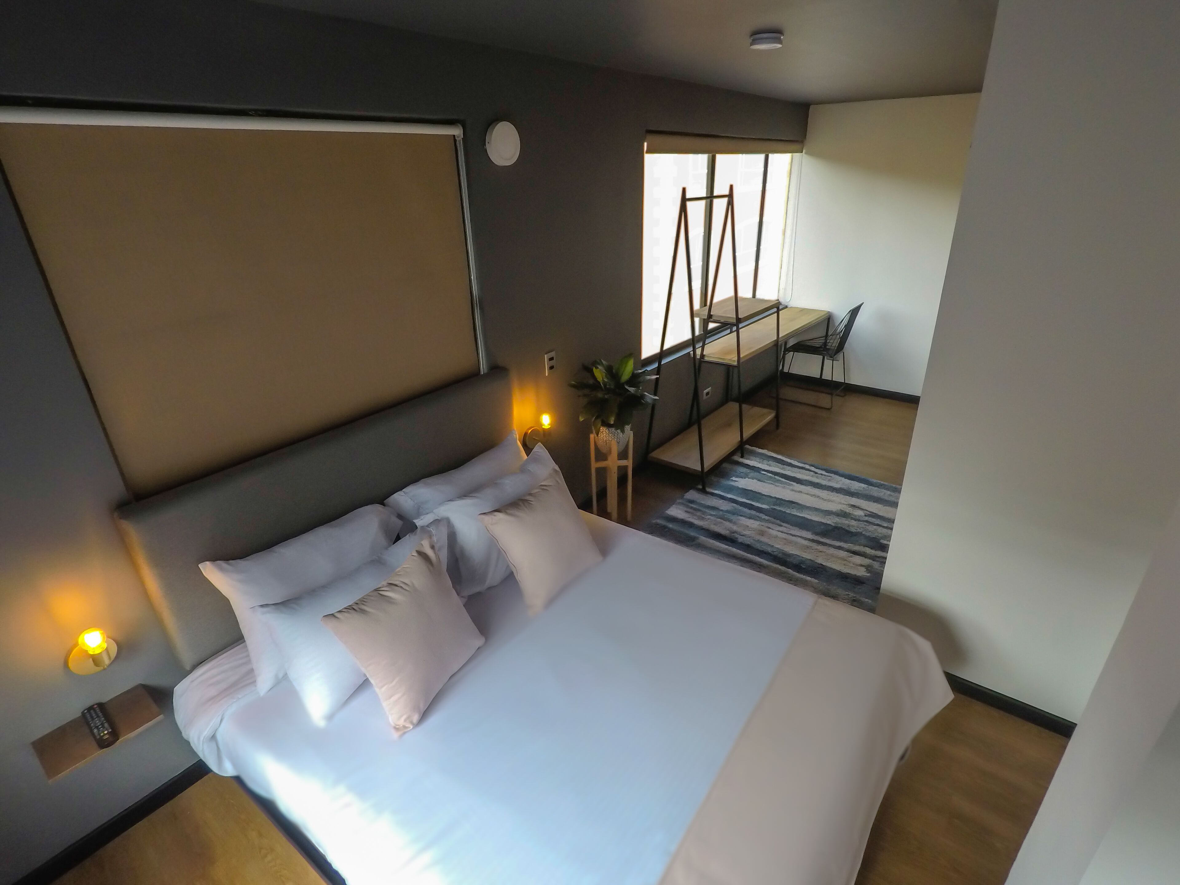 A modern hotel room with a large bed, bedside lamps, a desk, and a view of the outdoors.