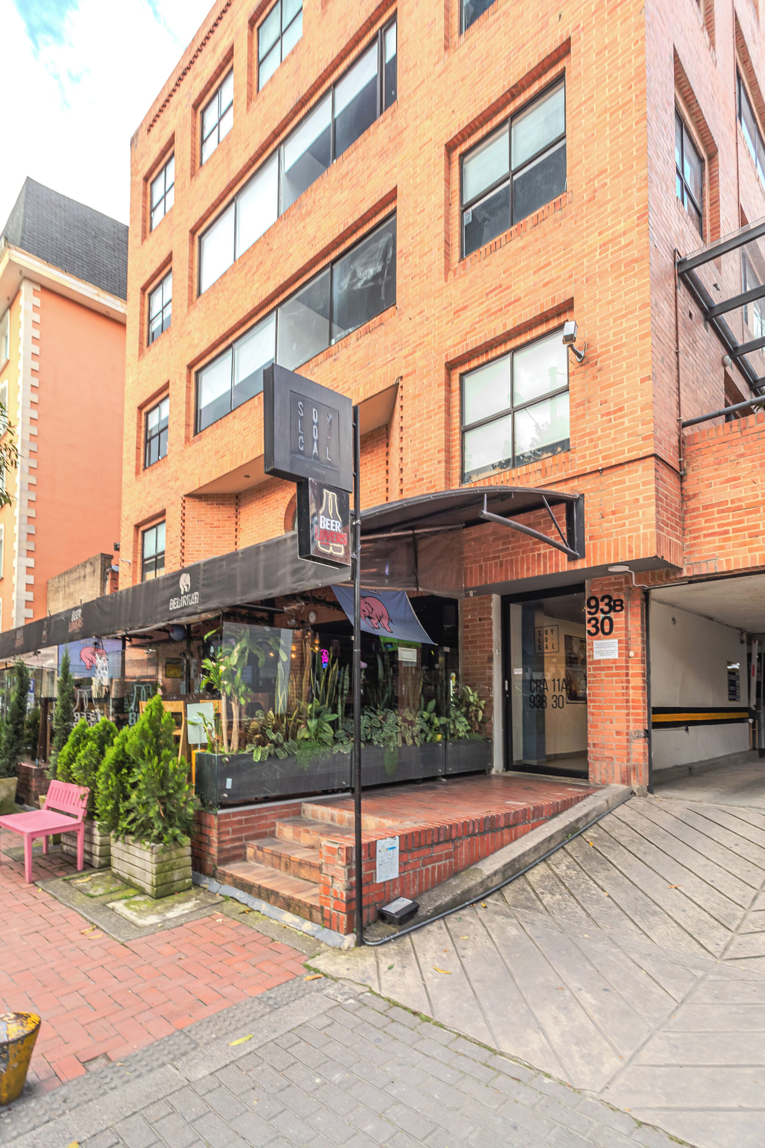 A multi-story brick building with a ground-level commercial space featuring a storefront with a black awning and signage.