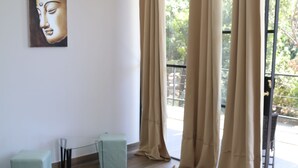 A bedroom with a bed, a window with curtains, a small table, and a chair. - La Jolla Hotel (Cóbano)