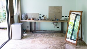 A kitchen with a marble floor, a refrigerator, a sink, and a window with a view of greenery. - La Jolla Hotel (Cóbano)