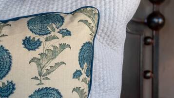 A bed with a white pillow and a decorative pillow with a floral pattern.