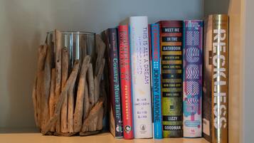 Una estanteria amb llibres i un vas de vidre amb branques.