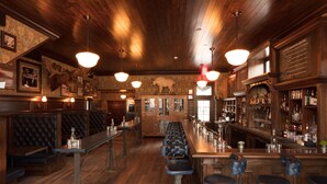 A bar with wooden flooring, leather booths, and a long counter with stools. - Public House Lofts (Crested Butte)