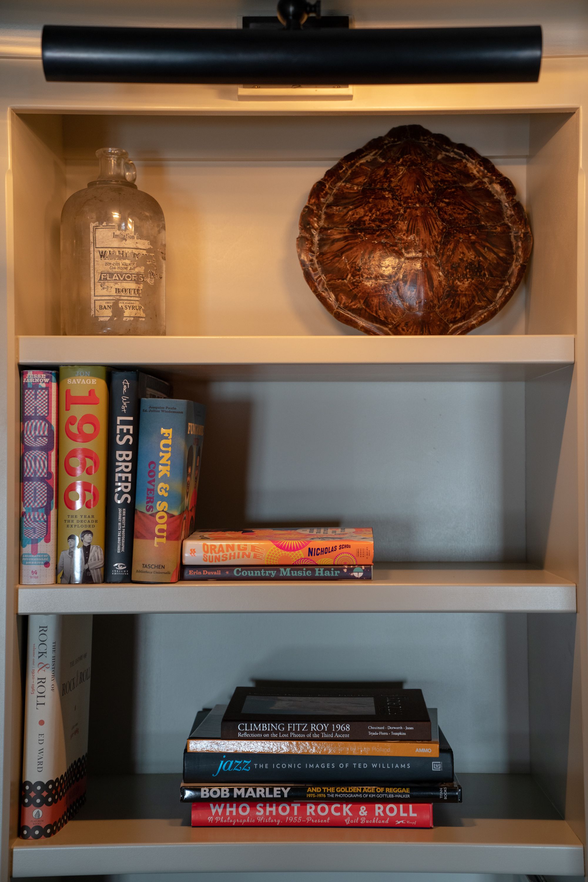 A bookshelf with books, a bottle, and a decorative object.