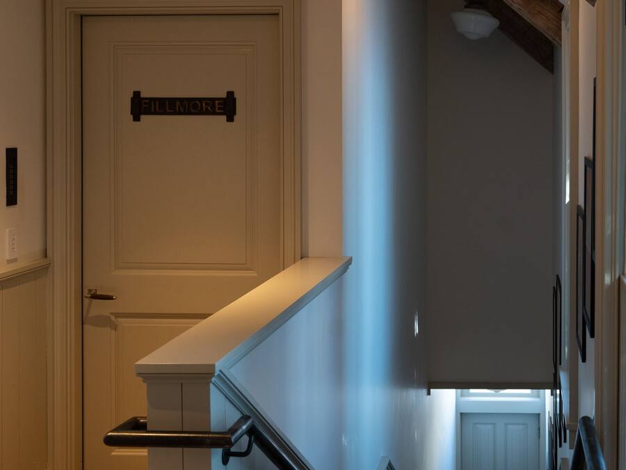 A staircase with wooden steps and black handrails, leading to a door with a sign above it.