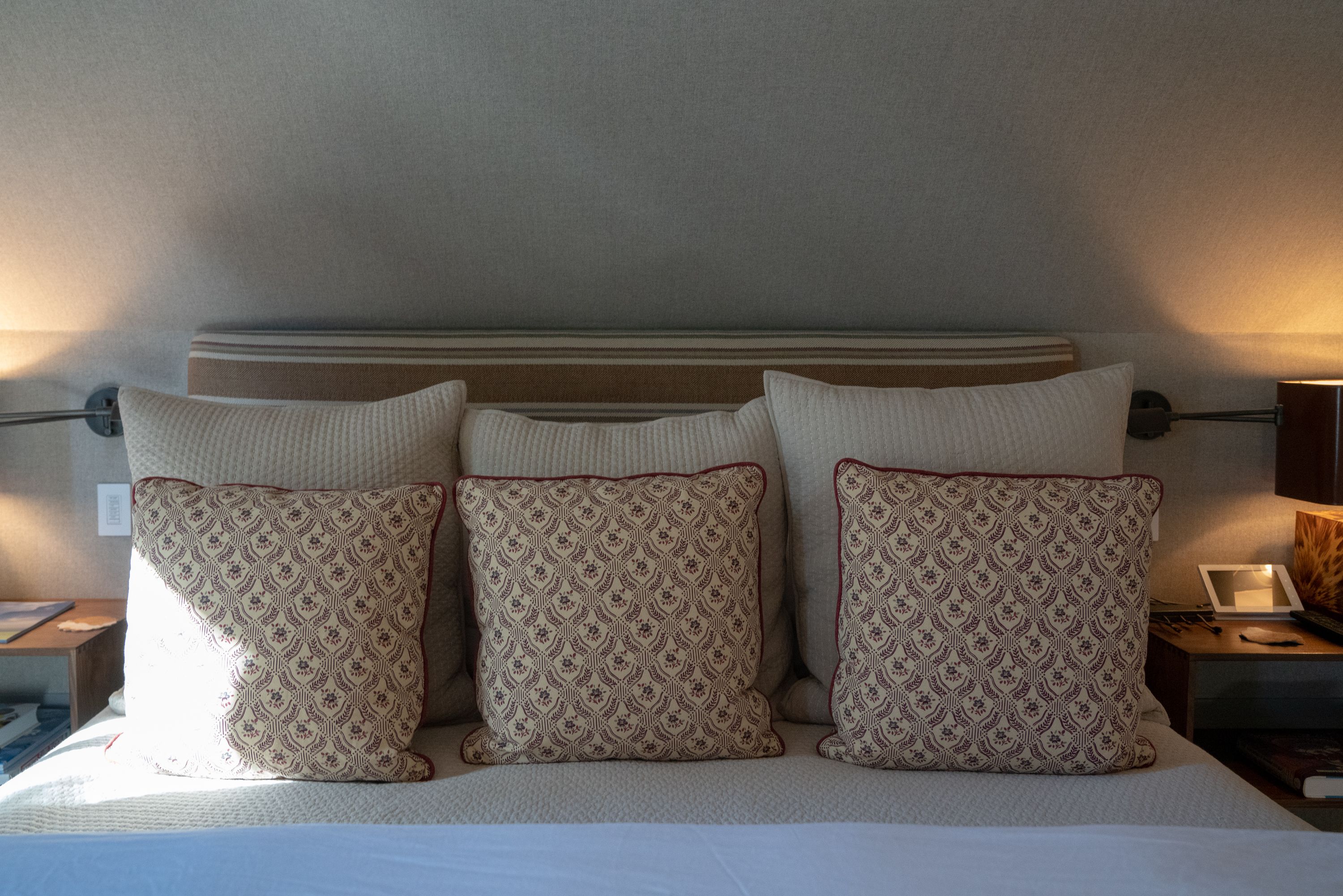 A neatly made bed with four patterned pillows and a striped headboard.