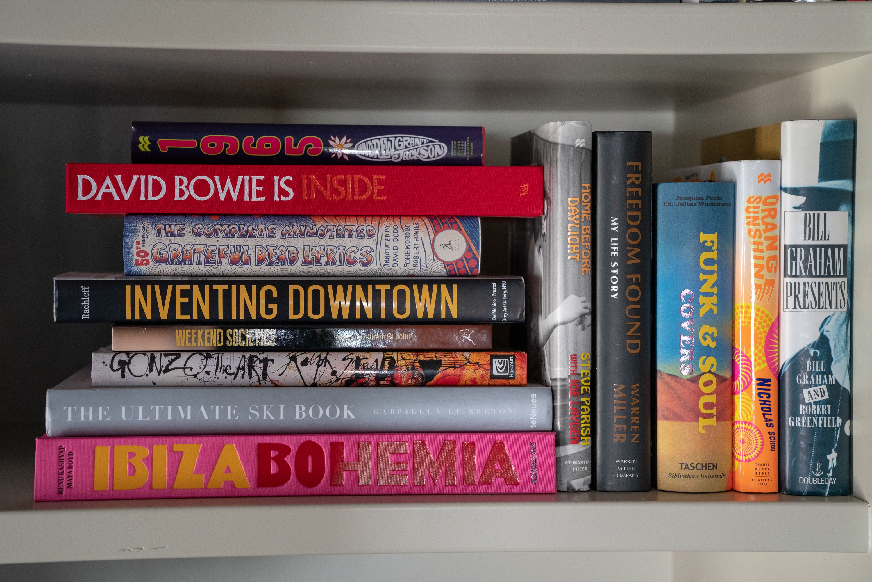 A bookshelf with various books, including titles like "David Bowie Is Inside" and "Inventing Downtown."