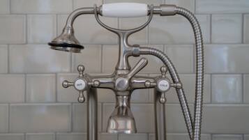 A bathroom with a vintage-style shower faucet and a flexible hose.