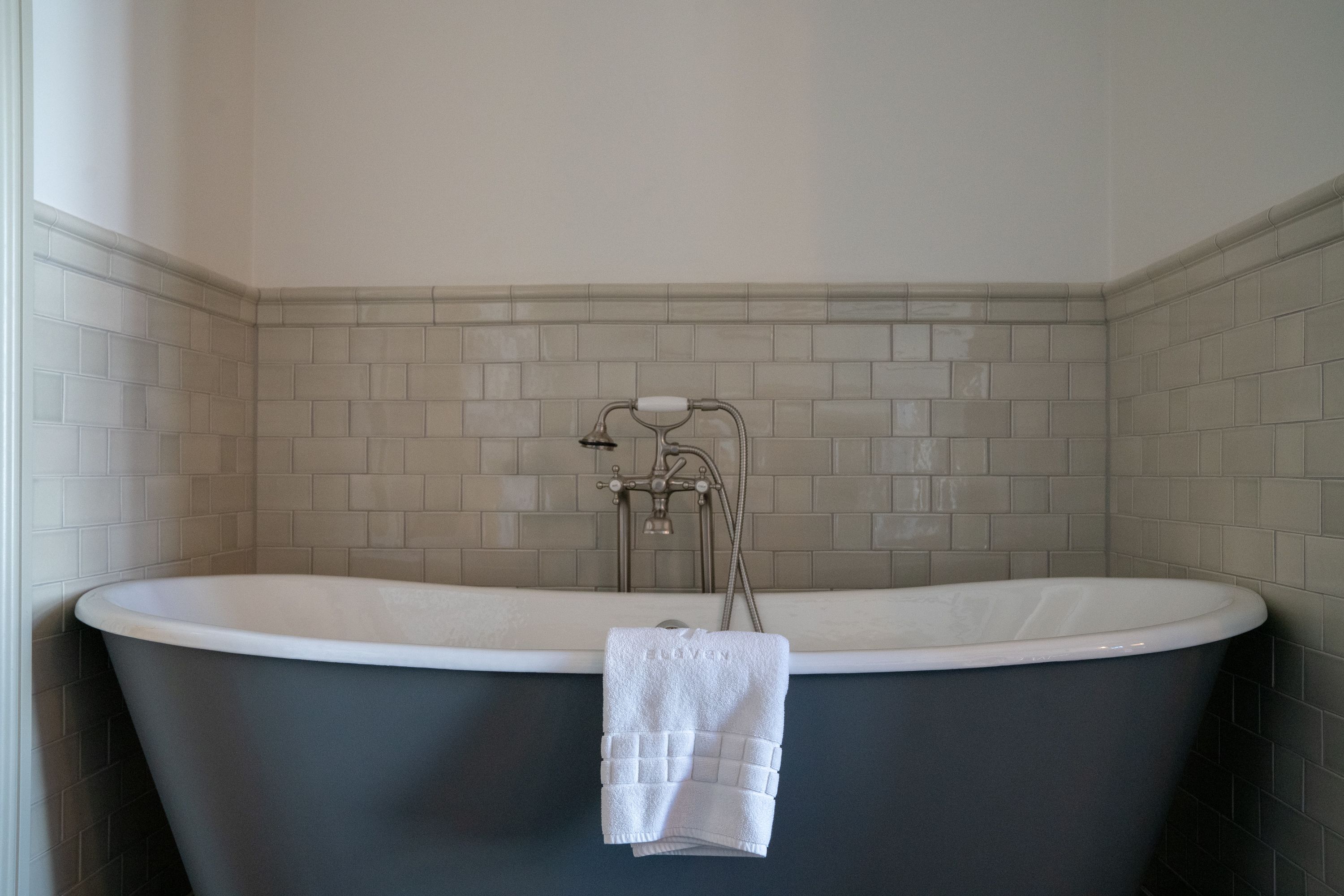 Un baño moderno con una bañera independiente, un perchero y una ducha con cabezal de ducha extraíble.