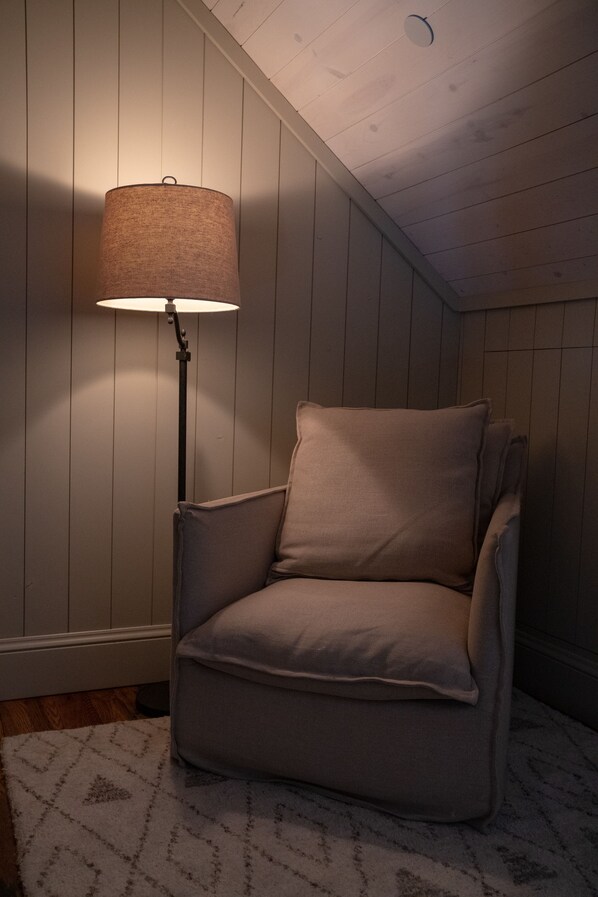 A corner room with a beige armchair, a floor lamp, and a patterned rug. - Public House Lofts (Crested Butte)