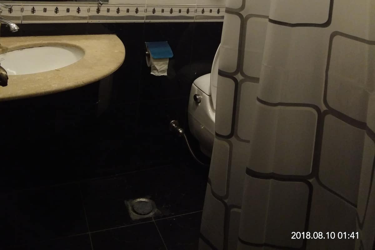 Un baño con lavamanos, espejo, toallero, inodoro y cortina de ducha.