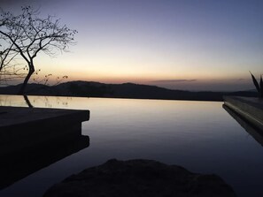 A tranquil infinity pool with a clear view of the horizon and distant hills.