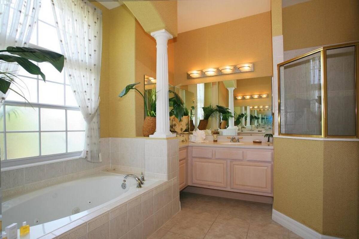 Une salle de bain avec une grande baignoire, un meuble-lavabo avec un miroir et des plantes en pot.