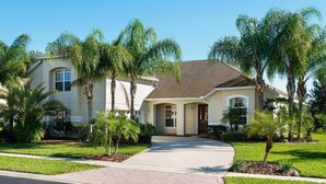 A two-story house with a driveway, palm trees, and a well-maintained lawn. - Formosa Gardens Homes by Atlas VH (Kissimmee)