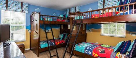 A bunk bed room with a desk, a ladder, and a window.