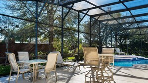 A covered patio with a pool, outdoor furniture, and a view of trees. - Formosa Gardens Homes by Atlas VH (Kissimmee)