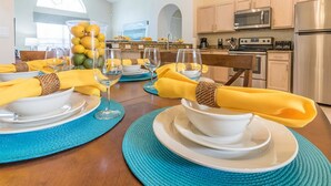 A dining table set with yellow napkins, white plates, and clear glassware.