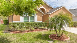 A residential house with a well-maintained lawn, a palm tree, and a green garage door.