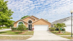 A single-story house with a garage, a front yard with a small tree, and a clear sky.