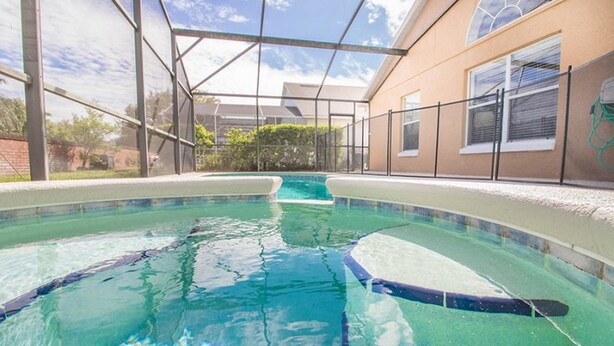 An indoor swimming pool with clear water, surrounded by a glass enclosure and a brick wall.