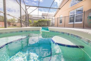 An indoor swimming pool with clear water, surrounded by a glass enclosure and a brick wall. - Oak Island Cove Homes by Atlas VH (Kissimmee)