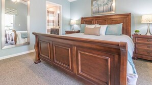 A bedroom with a large wooden bed, a nightstand, a dresser, and a mirror.