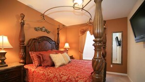 A bedroom with a four-poster bed, a television mounted on the wall, and a mirror. - Vista Cay Homes by Atlas VH (Orlando)