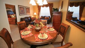 A dining area with a round table set for four, surrounded by wooden chairs. - Vista Cay Homes by Atlas VH (Orlando)