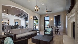 Un espace intérieur spacieux, aménagé avec des meubles en osier, un coin bar à l’arrière-plan et une cheminée.