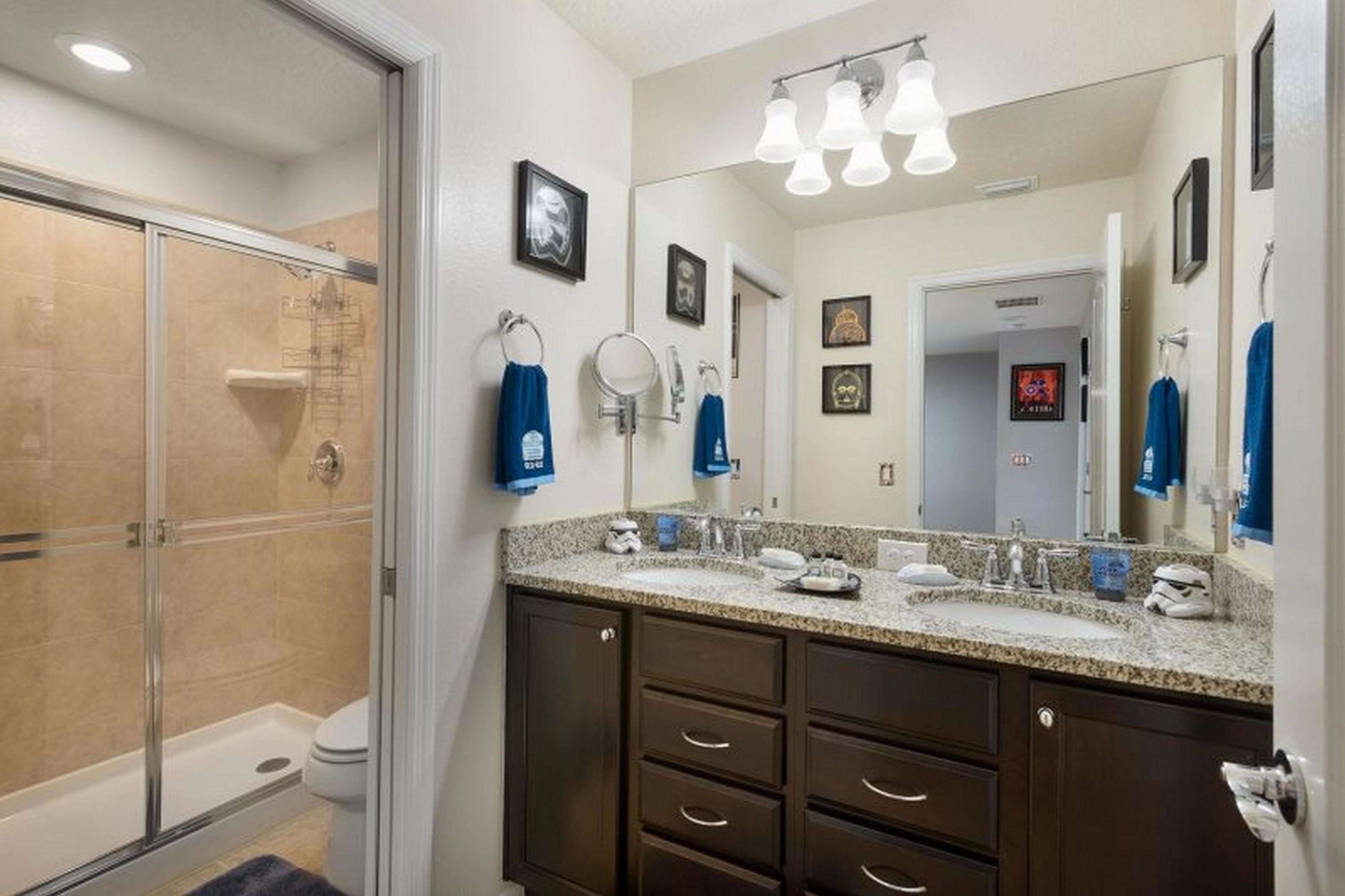 A modern bathroom with a glass shower enclosure, dual sinks, and a large mirror.