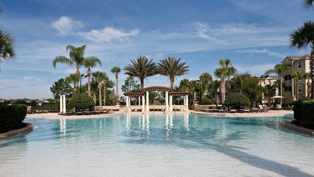 A large outdoor swimming pool surrounded by palm trees and a gazebo. - Windsor Hills Resort Homes by Atlas VH (Kissimmee)