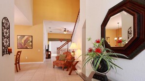 A spacious living area with a staircase, a sofa, a coffee table, and a potted plant. - Windsor Hills Resort Homes by Atlas VH (Kissimmee)