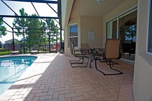 Un patio exterior con piscina, sillas y una mesa.