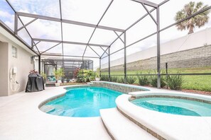 A covered outdoor swimming pool with a glass enclosure, surrounded by a landscaped garden and a stone wall. - Windsor Palms Resort (Kissimmee)