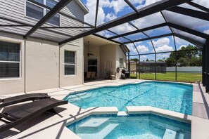 A swimming pool with a covered patio area, a ceiling fan, and a view of a house in the background. - Windsor Palms Resort (Kissimmee)