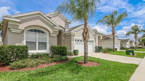 A residential house with a front yard, a palm tree, and a garage. - Windsor Palms Resort (Kissimmee)