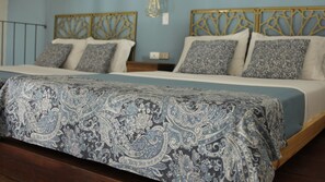 A bed with a patterned bedspread, a headboard with a geometric design, and a wall with a light switch. - Soy Local Centro Historico (Cartagena)