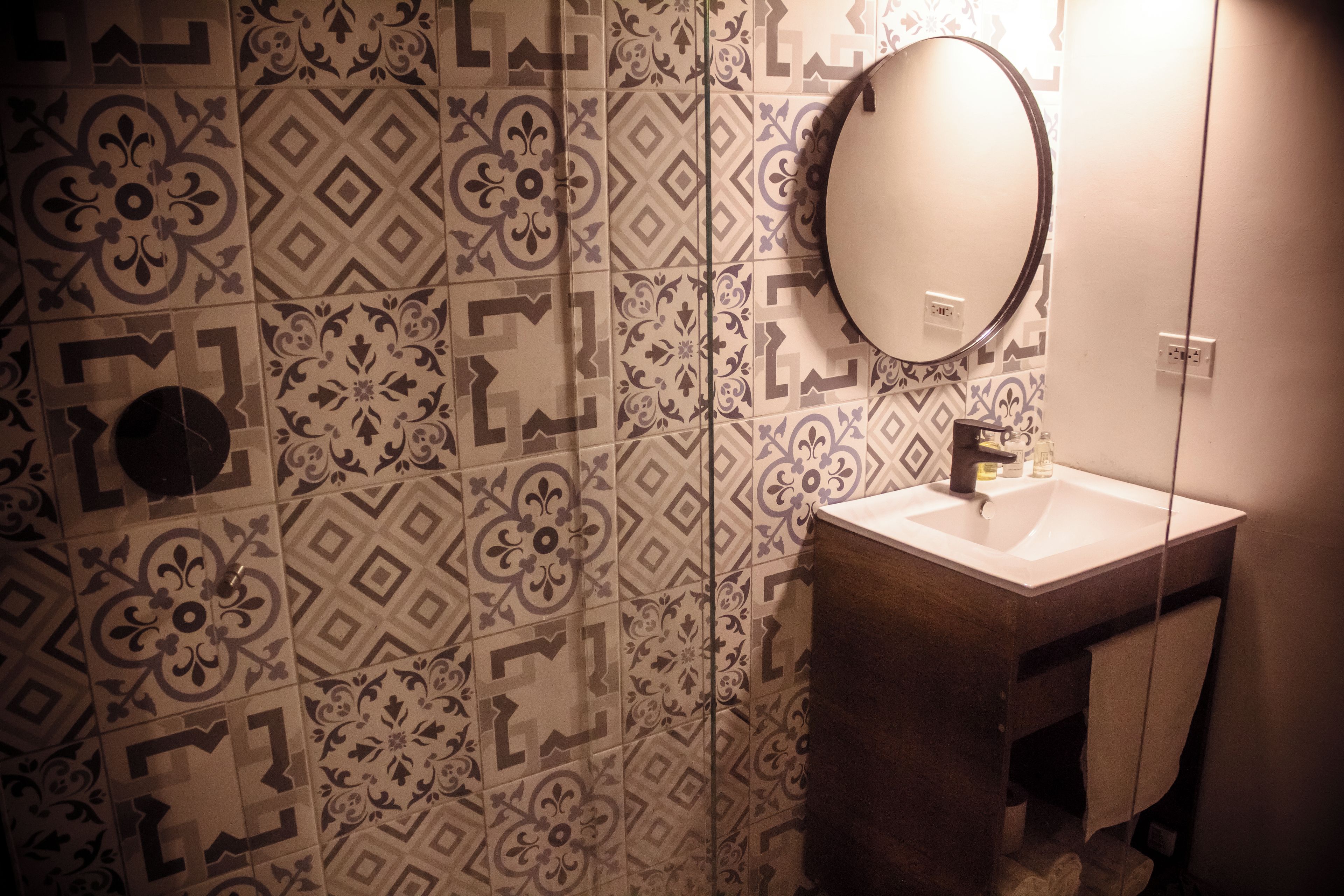 Een badkamer met betegelde vloer, een wastafel en een spiegel.