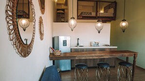 A modern kitchen with a wooden bar, stools, and pendant lighting.
