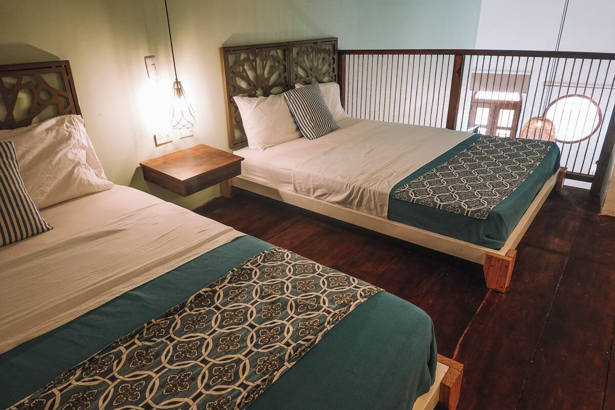 Two single beds with wooden headboards, a nightstand, and a hanging light fixture.