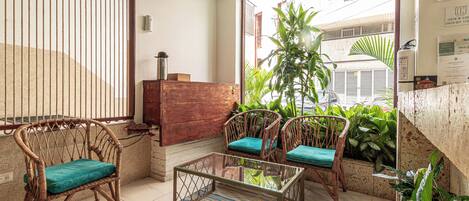 A room with wicker chairs, a glass table, and a view through a window.