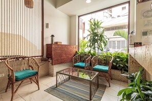 A room with wicker chairs, a glass table, and a view through a window. - Soy Local Centro Historico (Cartagena)