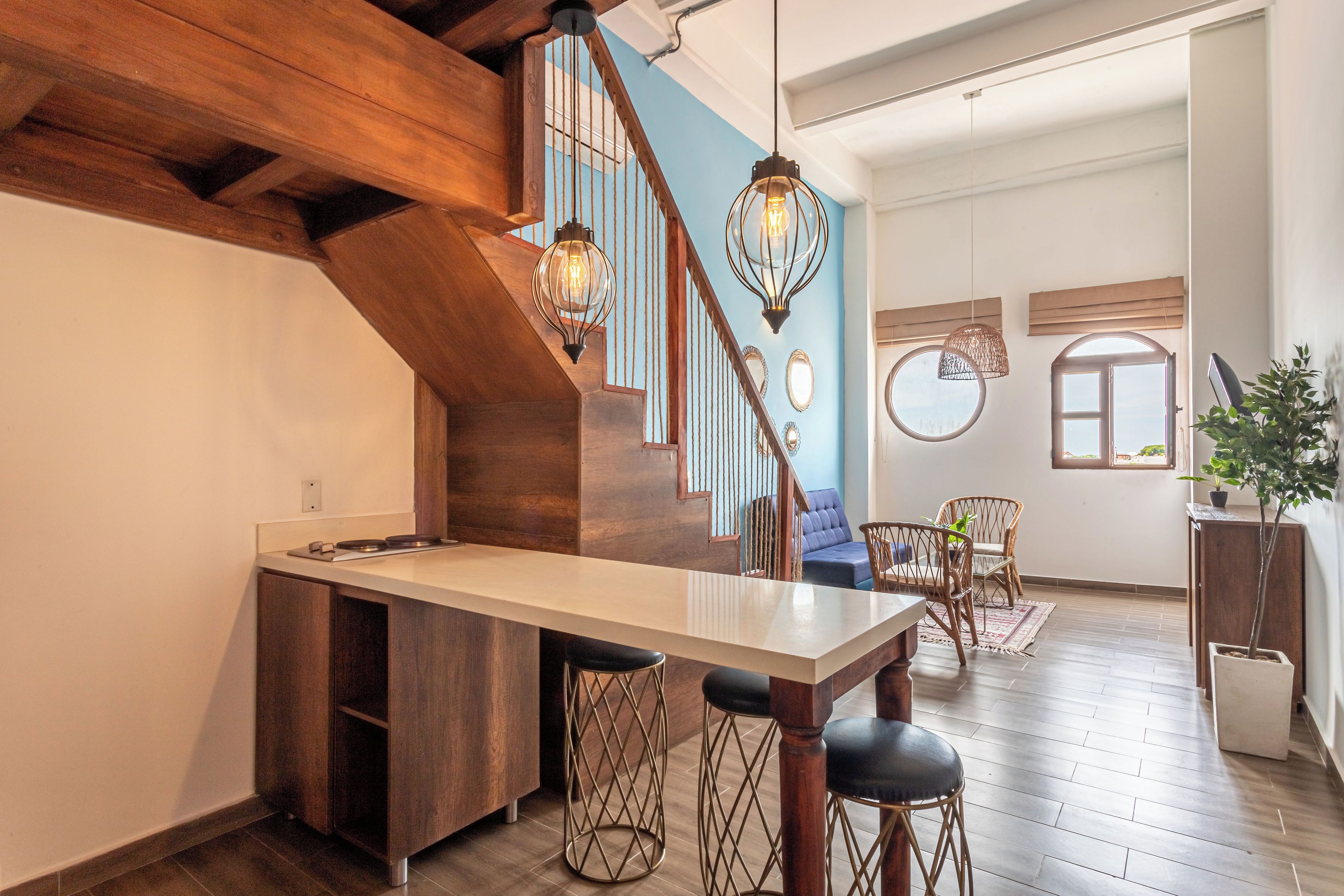 A kitchen with a wooden island, a dining area with a table and chairs, and a staircase with a blue wall.