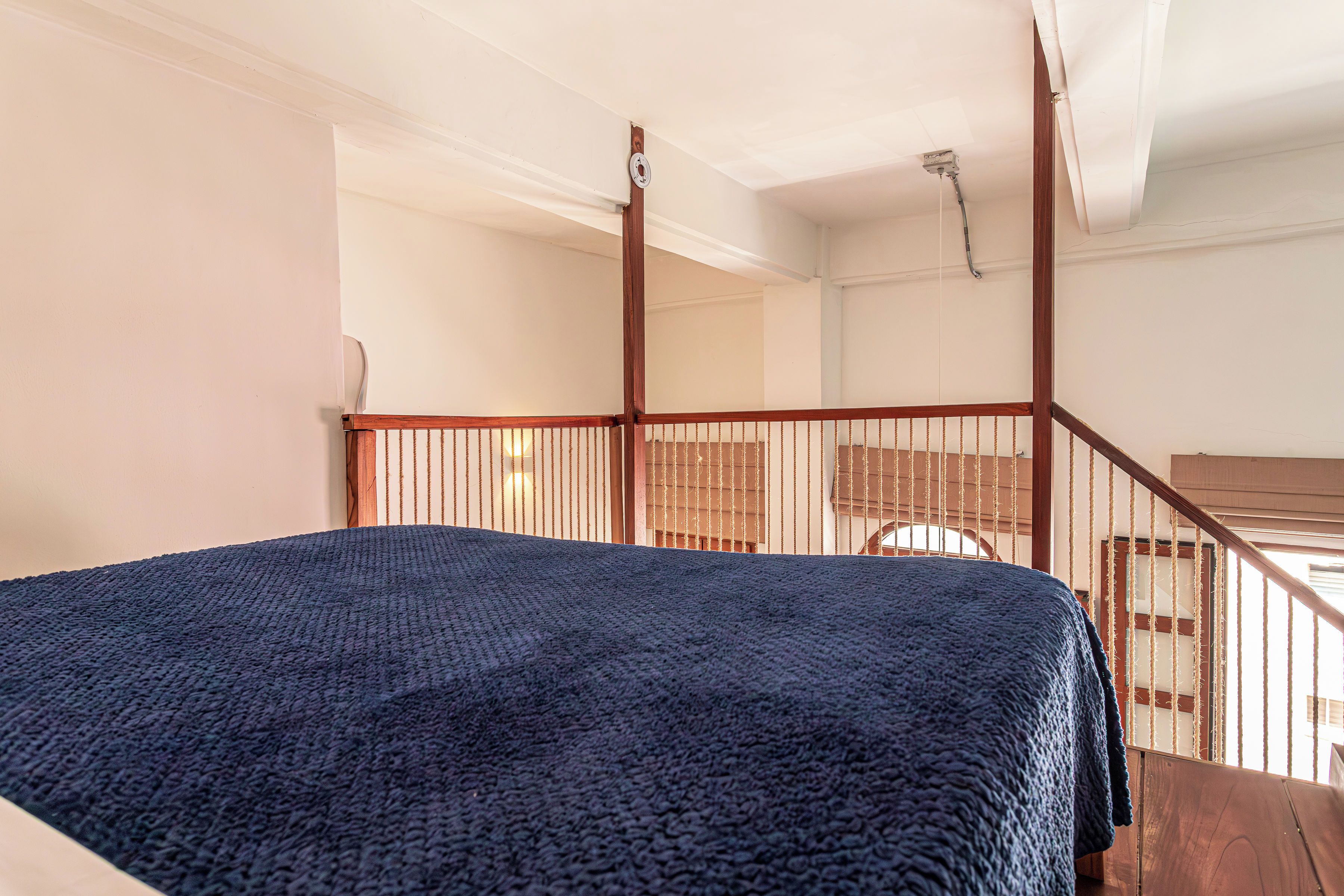 Ein Schlafzimmer mit Bett, Holzwand und Blick ins Freie.