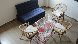 A living room with a dark blue sofa, two wicker chairs with cushions, a glass coffee table, and a patterned rug. - Soy Local Centro Historico (Cartagena)