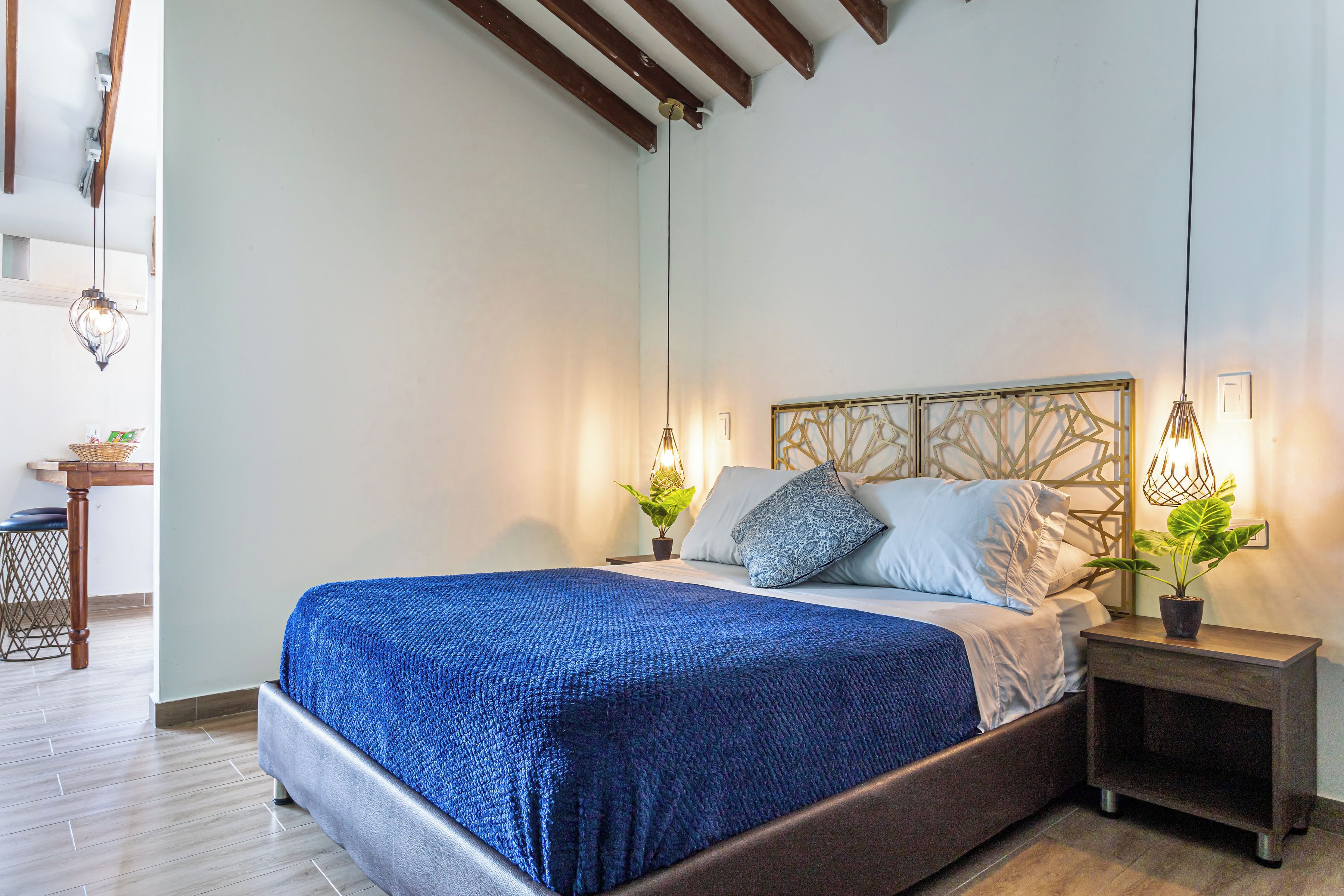 A bedroom with a large bed, bedside tables, a wooden floor, and a ceiling with exposed beams.